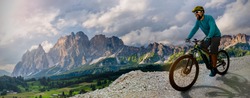 Man cycling on electric bike, rides mountain trail.  Man riding on bike in Dolomites mountains landscape. Cycling e-mtb enduro trail track. Outdoor sport activity.