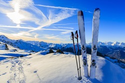 Ski in winter season, mountains and ski touring equipments on the top at sunrise.