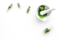 Herbal medicine. Herbs in mortar bowl and in small bottles on white background top view copy space