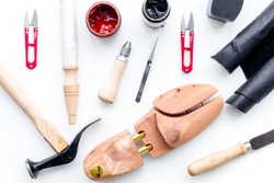 Tools for shoe repair. Hummer, awl, knife, sciccors, wooden shoe, insole, paint and leather. White background top view pattern