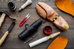 Tools for shoe repair. Hummer, awl, knife, sciccors, wooden shoe, insole, paint and leather. Dark wooden background top view pattern