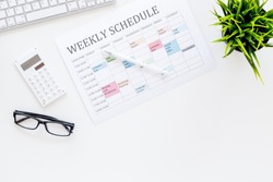 Weekly schedule of manager, office worker, pr specialist or marketing expert. Table with multicolored blocks on white office desk with computer, glasses, calculator top view copy space