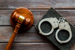 Arrest concept. Handcuffs near judge gavel on dark wooden background top-down