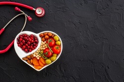 Cholesterol diet concept. Healthy food in heart shaped dish with stethoscope
