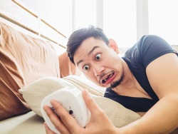 Funny face Asian man shocked as he wakes up late for an appointment.
