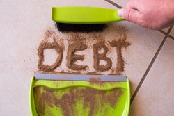 Sweep debt clean concept with debt written in dirt on a floor and a person is about to sweep the debt dirt in a dust pan using a small hand broom