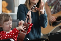 Mother take musical instrument from daughter hands to show how to play