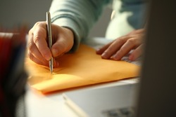 Male hand fills out the address on yellow postage envelope