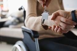 Realtor give keys from new accommodation to woman in wheelchair