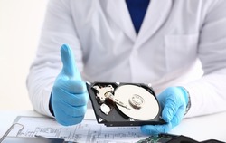 Man in uniform hold disassembled hard drive from computer, hdd and reader, show thumbs up