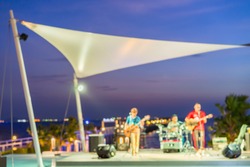 Blur music band performing on stage with reflection on swimming pool beside the beach