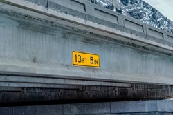 Close up view of a vertical clearance sign at the side of a concrete bridge