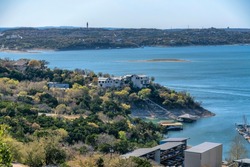 Panoramic view of the scenic Lake Austin in Texas with calm water and buildings. Aerial view of the water reservoir with surrounding houses in a residential area with lush trees.