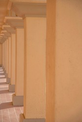 Concrete pillars on a passageway at downtown Tucson, Arizona. Row of painted beige concrete pillars on a corridor with red tile flooring.