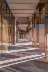 Passageway with tile pillars and concrete pavement in downtown Tucson, Arizona. Walkway outside the building with glass walls on the left across the pillars on the right.