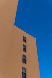 Multi-storey building with painted brown wall and single-hung windows in Destin, Florida. Low angle view of a building with clear blue sky background.