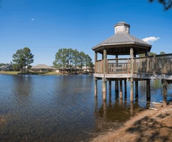 Gazebo over the freshwater near the bungalow houses at Navarre, Florida. Gazebo facing the waterfront bungalow homes with trees at the front and blue sky background.