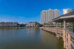 Residential area with waterfront views and boardwalk in Destin, Florida. There is a boardwalk with gazebo on the right over the water against the modern apartments and blue sky at the background.