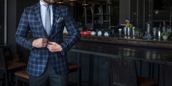 Man in expensive custom tailored suit standing and posing inside of a bar