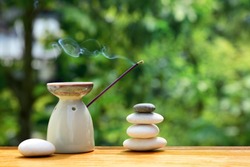 Aroma lamp with incense stick and zen stones on a wooden table. Zen concept. 