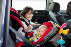 Little baby boy and his older brother, traveling in car seats, going on a holiday, preschool boy playing with mobile phone