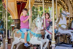 Children going on Merry Go Round, kids play on carousel in the summer