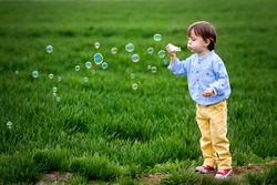 Little boy blowing soap bubbles, closeup portrait