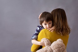 Sad little child, boy, hugging his mother at home, isolated image, copy space. Family concept