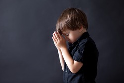 Little boy praying, child praying, isolated black background