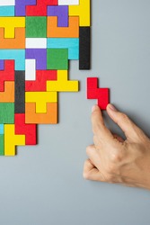 hand connecting geometric shape block with colorful wood puzzle pieces. logical thinking, business logic, Conundrum, decision, solutions, rational, mission, success, goals and strategy concepts