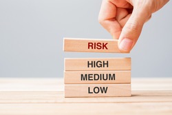 Businessman hand placing or pulling wooden block with Risk text over High Medium and Low. planning, risk Management, economic, finance and corporate Concepts