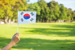 hand holding Korea flag on nature background. National Foundation, Gaecheonjeol, public Nation holiday, National Liberation Day of Korea and happy celebration concepts
