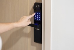 Hand press PIN number for smart digital door lock while open or close the door at home or apartment. NFC Technology, Fingerprint scan, keycard, smartphone and contactless lifestyle concepts