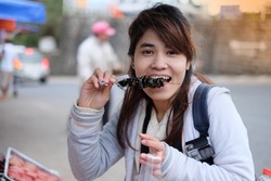 Portrait of smiling woman eating, young asian is happy to eat, a female tourist enjoy eating traditional street food in Dalat, Vietnam