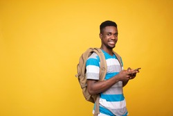 a young black man carrying a backpack using his mobile phone, smiling