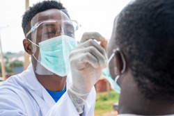 an african lab scientist taking nasal sample from a man