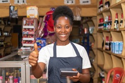 female african store attendant smiling and gives a thumbs up