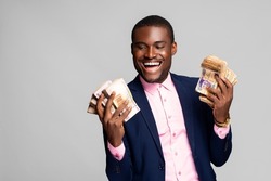 happy young african man holding a lot of money that he has won, feeling excited