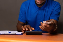 young african man holding some money and doing some calculations