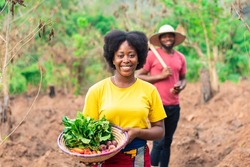 portrait of a beautiful female african farmer carrying basket of vegetable