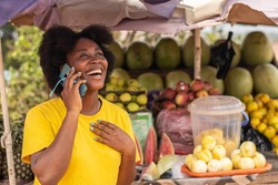 excited african lady making a phone call in a market