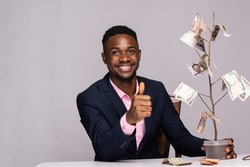 african businessman sitting next to a plant with money as leaves