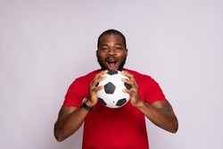 excited young black man holding a soccer ball rejoicing