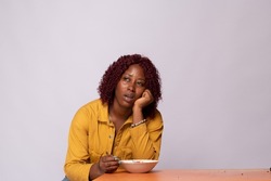 hungry black lady holding an empty plate and looking unhappy