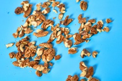 Scattered pieces of pulp and whole walnut on blue background