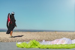 Paraglider on professional flight suit and helmet looking at the sky at the top of a hill ready for take off. Copy space for advertisement or text on right side