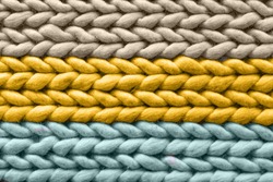 Texture of warm woolen multicolored rug, background. Colors Sail Champagne, Fortuna Gold, Tidewater Green. Pigtail pattern, soft focus.
