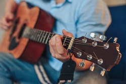 a man plays the guitar. hands hold the neck of the guitar. the musician is playing a tune.