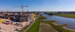 Wide aerial panoramic view on a construction site of the new Noorderhaven neighbourhood on the left and river IJssel that flows passed Hanseatic Dutch city of Zutphen on the right