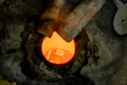 Glory hole close up of orange and red tones of super heated mix of metals tin and copper melting in special furnace construction. Bronze casting process and manual labor concept.